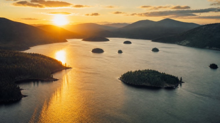 Aerial still: wooded islands in a lake at sunset