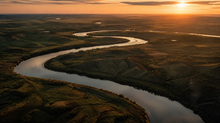 Aerial still: a river winding across open plains at dusk